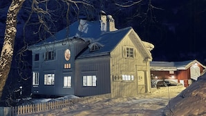 A two-story wooden house with a snow-covered roof, a picket fence, and a visible chimney. - Historic Executive Residence from 1907 (Telemark)