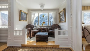 A room with a fireplace, leather armchairs, a wooden coffee table, and a view of snow-covered mountains through large windows. - Historic Executive Residence from 1907 (Telemark)