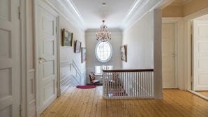 A hallway with wooden floors, white walls, and a chandelier. - Historic Executive Residence from 1907 (Telemark)