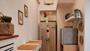 Uma cozinha pequena com piso de madeira, geladeira branca e forno embutido.