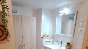 Um banheiro com toucador branco, espelho e porta-toalhas.