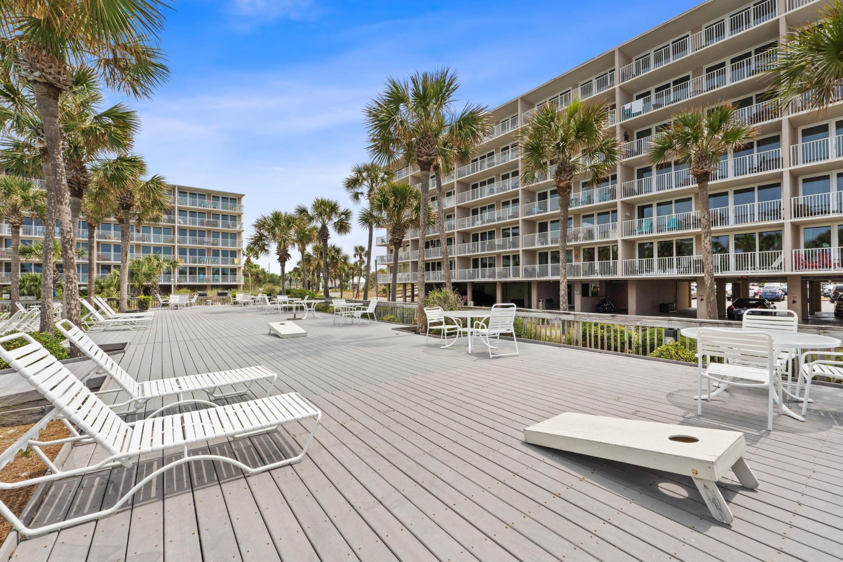 A hotel with a pool area, outdoor seating, and palm trees.
