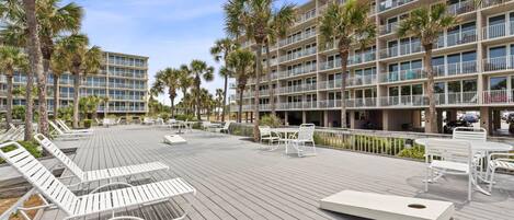 A hotel with a pool area, outdoor seating, and palm trees.