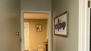 Ein Flur mit Holzboden, einer Tür am Ende und einem Willkommen-Schild an der Wand.