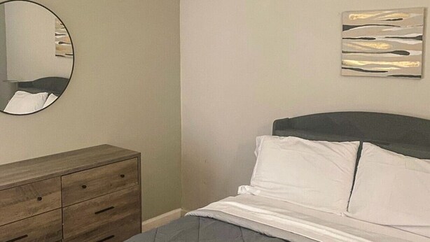 Ein Schlafzimmer mit einem Bett, einem Schminktisch, einem Spiegel und einem Wandbild.