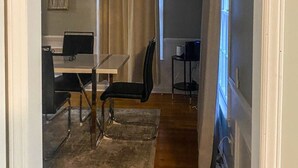 Ein Zimmer mit Esstisch, Stühlen, einem Computer und einem fensterbepflanzten Fenster.
