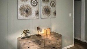 Eine Holzkommode mit Schubladen, ein Spiegel und Dekorationselemente vor einer Wand mit zwei runden Wandbildern.