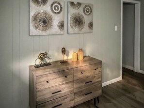 A wooden dresser with drawers, a mirror, and decorative items against a wall with two circular wall art pieces.