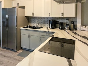 Eine moderne Küche mit Einbauofen, Kühlschrank, Spüle und Kaffeemaschine.