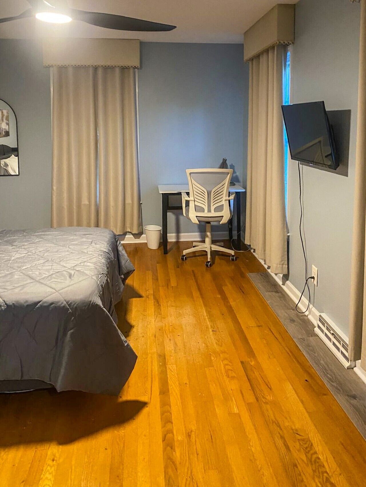 Ein Hotelzimmer mit einem Bett, einem Schreibtisch, einem Sessel, einem Fernseher und einem Deckenventilator.