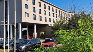 A multi-story building with a flat facade, several windows, and a parking area with cars. - Sympo Apartaments (Kraków)