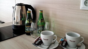 A kitchen counter with a coffee maker, two cups, two glasses, and two bottles of beer. - Sympo Apartaments (Kraków)