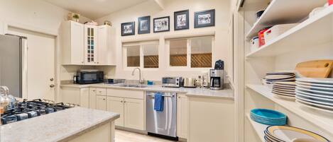 A modern kitchen with white cabinets, stainless steel appliances, and a central island.