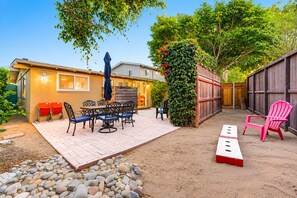 Una zona patio con tavolo e sedie, una recinzione in legno e una sedia rossa.