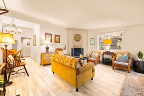 Ein Wohnzimmer mit einer Couch, Sesseln, einem Kamin und einem Essbereich mit Tisch und Stühlen.