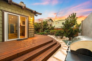 Eine Terrasse mit Holzstufen, einem Grill und einem Haus mit Schiebetür.