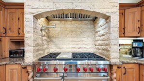 Une cuisine dotée d’une arche en pierre, d’appareils électroménagers en acier inoxydable et d’armoires en bois.