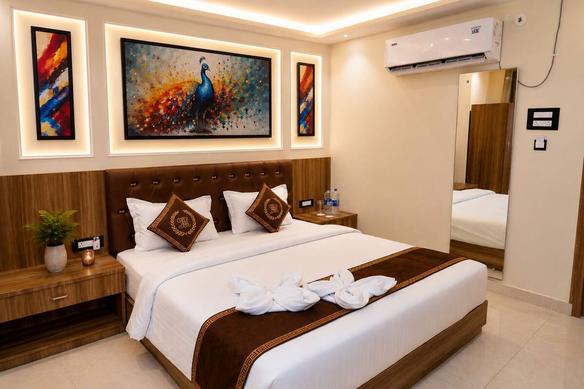 Una habitación de hotel con una cama grande, una mesita de noche con una planta, un espejo y obras de arte en las paredes.