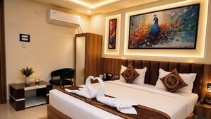 A hotel room with a large bed, a mirror, a desk, a chair, and two paintings on the wall.