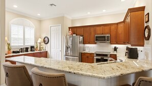 A kitchen with wooden cabinets, a granite countertop, stainless steel appliances, and a large window with blinds. - Upscale 4-bedroom house in peaceful Naples with cool AC, Pool, and Spa (Naples)