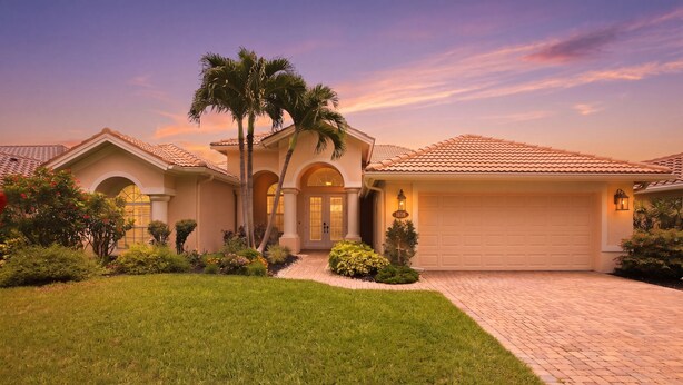 A residential house with a driveway, palm trees, and a garage. - Upscale 4-bedroom house in peaceful Naples with cool AC, Pool, and Spa (Naples)