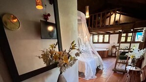 A rustic interior with a wooden bench, a vase of flowers, a mirror, and a bed with a canopy. - Lenna por GEstores (Huasca De Ocampo)