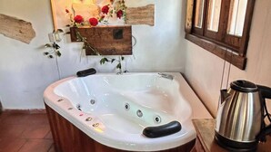 A hot tub in a rustic room with stone walls, a wooden ceiling, and a window. - Lenna por GEstores (Huasca De Ocampo)
