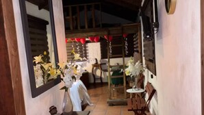 A corridor with a wooden ceiling, a mirror, a vase with flowers, a small bear figurine, and a table with chairs. - Lenna por GEstores (Huasca De Ocampo)