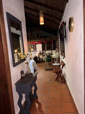 A corridor with a wooden ceiling, a mirror, a vase with flowers, a small bear figurine, and a table with chairs. - Lenna por GEstores (Huasca De Ocampo)