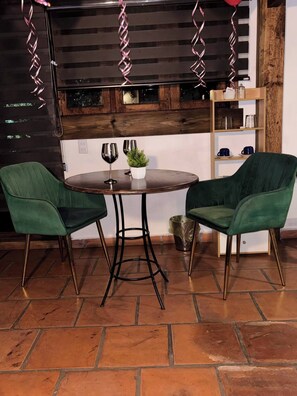 A round table with two green chairs, a potted plant, and two wine glasses. - Lenna por GEstores (Huasca De Ocampo)