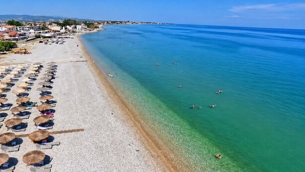 A beach with clear water, umbrellas, and people swimming. - Villa Mare Lechaio - A Beachside Hideaway (Lechaio)