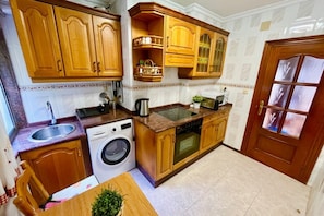 A compact kitchen with wooden cabinets, a washing machine, and a sink. - 309A La Casina del Lavadero - Cudillero (Cudillero)