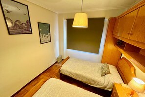 Un dormitorio con dos camas, una ventana, muebles de madera y decoración en la pared.