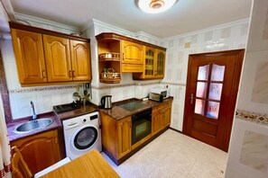 Eine kleine Küche mit Holzausstattung, einer Waschmaschine und einer Mikrowelle.