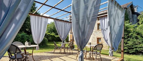 An outdoor seating area with tables and chairs under a pergola structure.
