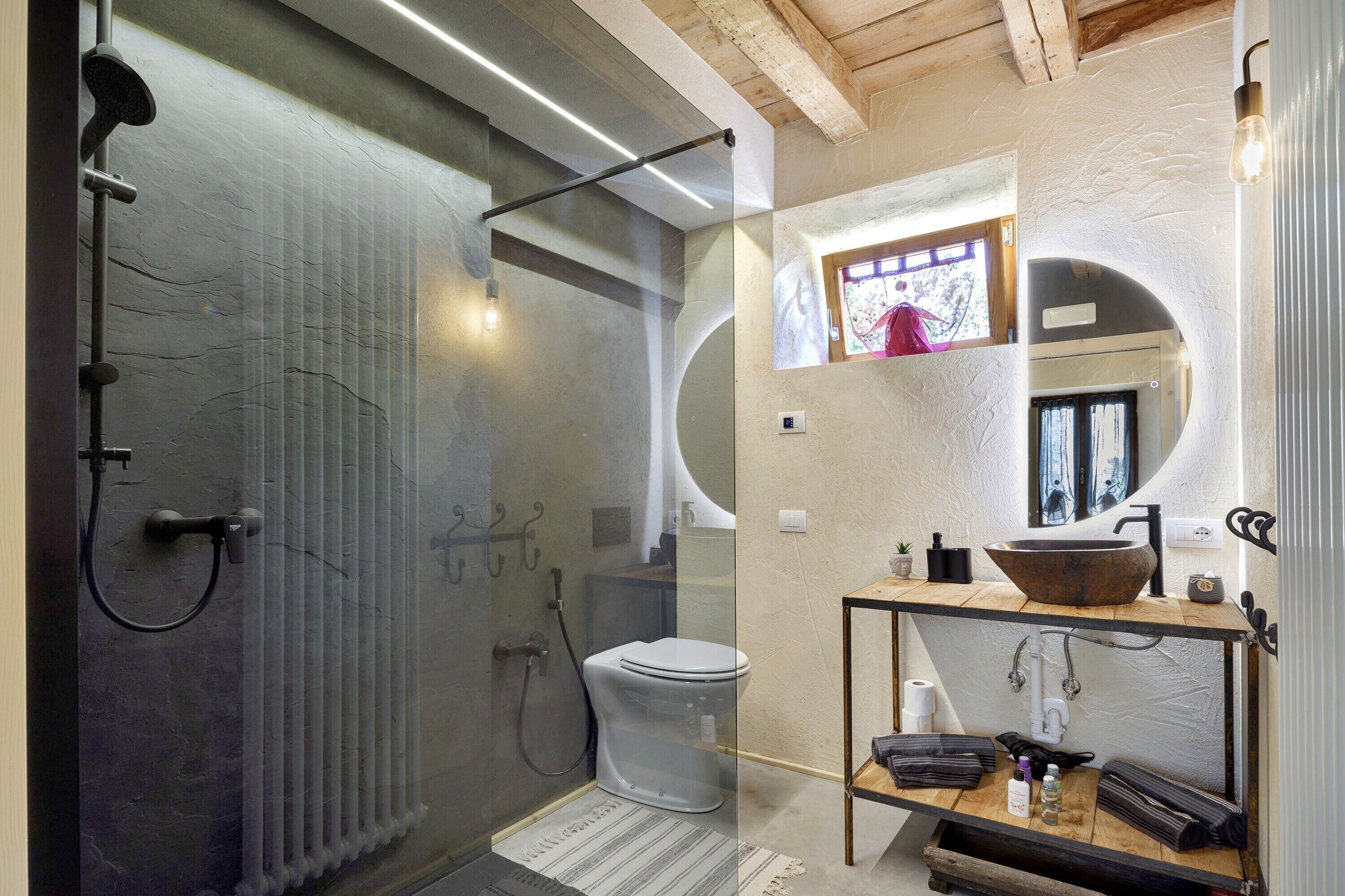 A modern bathroom with a glass shower enclosure, a toilet, and a vanity with a large bowl sink.