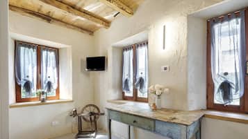 Una stanza rustica con travi in legno, una rocchetto, un tavolo d'epoca e un televisore montato a parete.