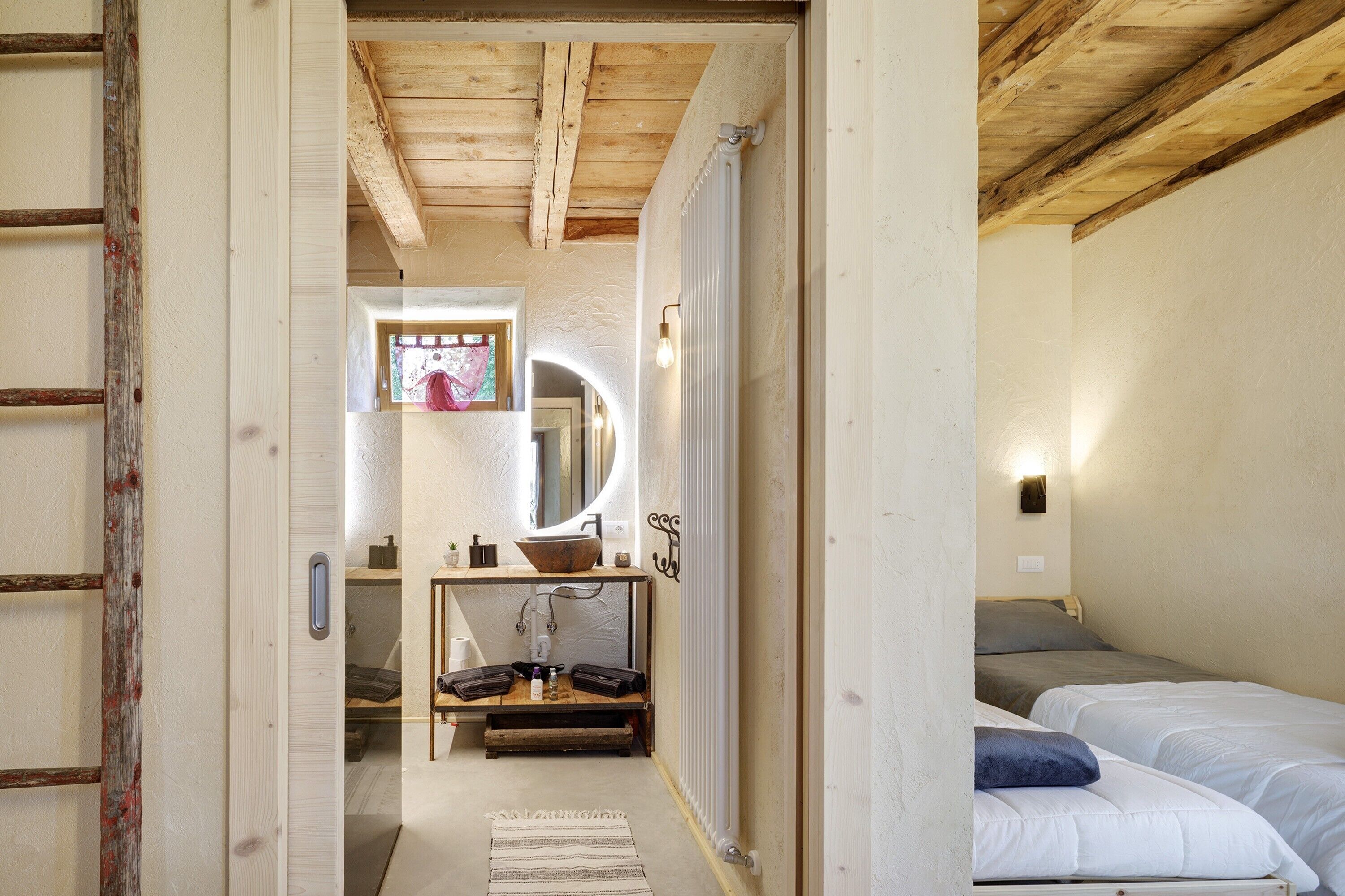 A bedroom with a bed, a bedside table, a mirror, and a window.