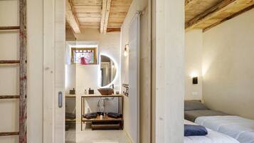 A bedroom with a bed, a bedside table, a mirror, and a window.