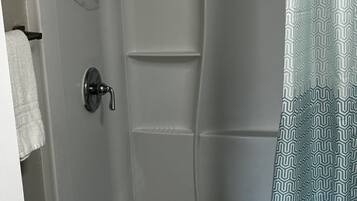 Ducha con puerta blanca, toallero y cortina de ducha.
