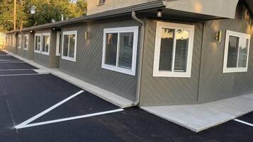 Filas de habitaciones de motel, cada una con entrada privada, un estacionamiento y la fachada del edificio.