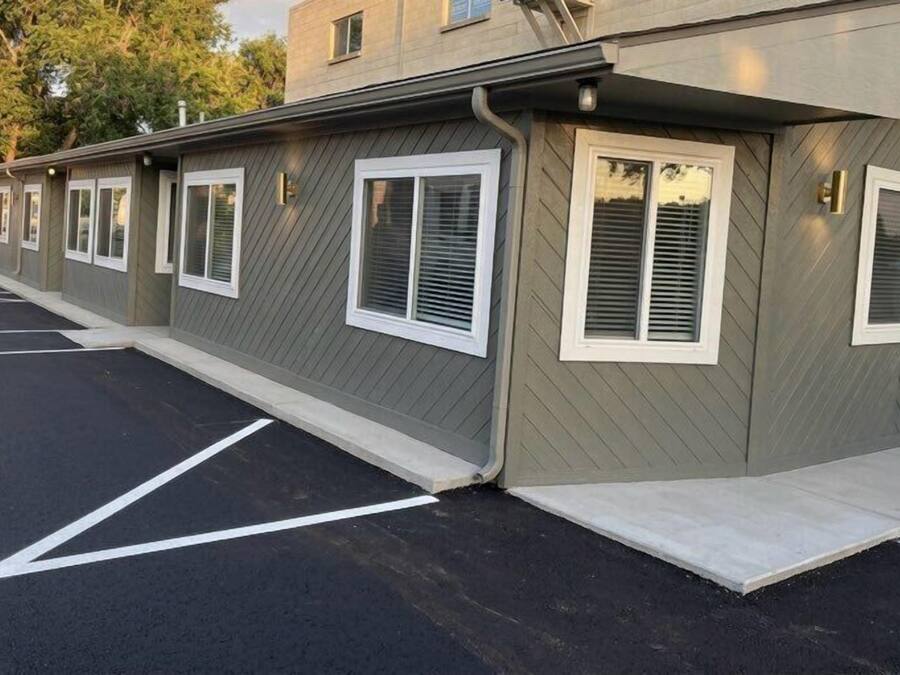 Filas de habitaciones de motel, cada una con entrada privada, un estacionamiento y la fachada del edificio.