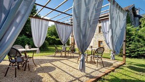 An outdoor seating area with tables and chairs under a pergola structure.