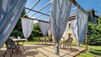 Un espace extérieur aménagé avec des tables et des chaises, installé sous une pergola.