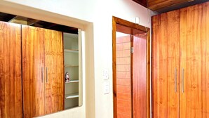 Habitación con armarios de madera, pared blanca y toma de corriente visible.