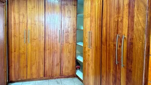 Un armario de madera con dos pomos, suelo de baldosas y techo de madera.