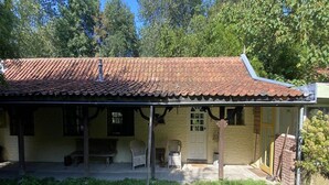 A single-story building with a tiled roof, a porch with chairs, and a door. - Nature Escape Home Near Veere (Gapinge)