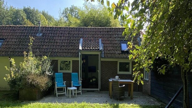 A house with a tiled roof, a door, and a small patio area with two chairs and a table. - Nature Escape Home Near Veere (Gapinge)