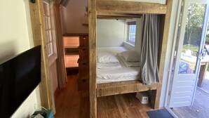 A bunk bed room with a TV, wooden floor, and a door leading outside. - Nature Escape Home Near Veere (Gapinge)
