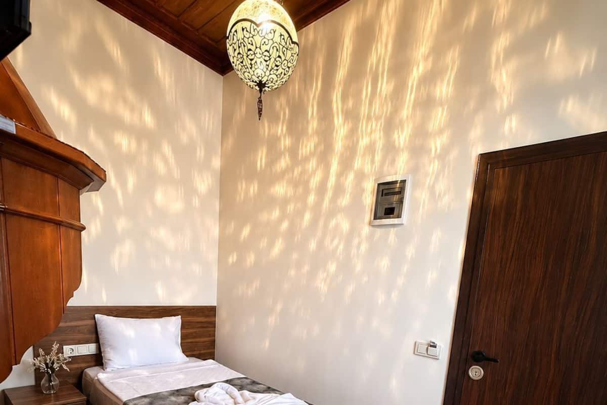 Un dormitorio con una cama de madera, una mesita de noche, un calentador en la pared y una puerta.